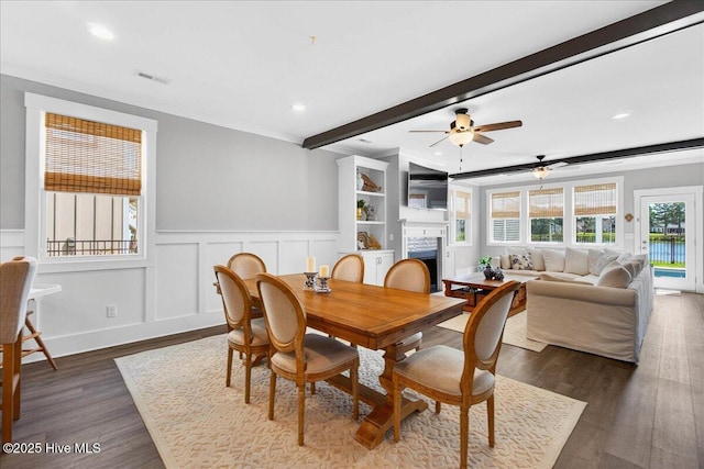 385 Summerhouse Dr, Holly Ridge, NC 28445 - dining space with a fireplace, beamed ceiling, dark wood finished floors, a wainscoted wall, and recessed lighting