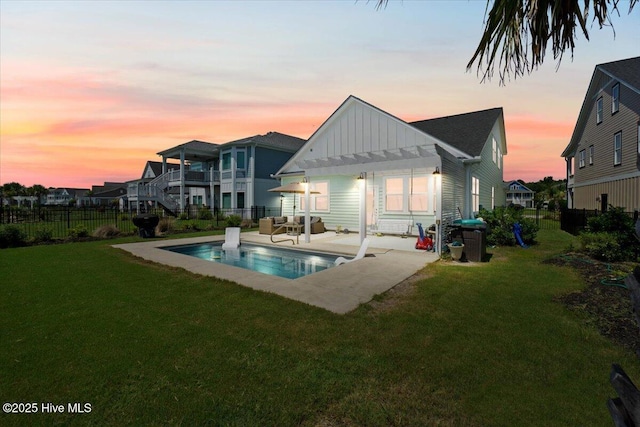385 Summerhouse Dr, Holly Ridge, NC 28445 - back of house at dusk with board and batten siding, a fenced backyard, a patio area, and a pergola