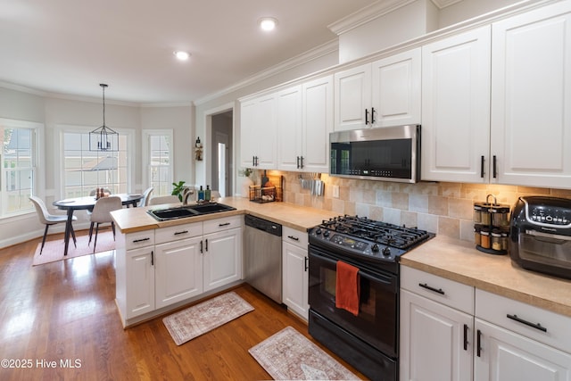 4409 Pinehurst Dr N, Wilson, NC 27896 - kitchen featuring appliances with stainless steel finishes, wood finished floors, light countertops, crown molding, and a peninsula