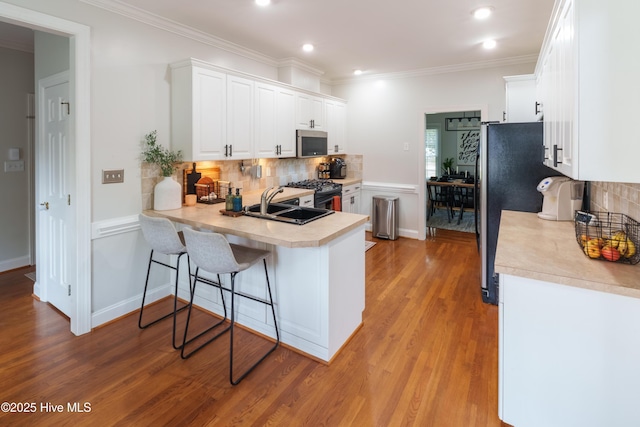 4409 Pinehurst Dr N, Wilson, NC 27896 - kitchen with stainless steel appliances, white cabinetry, backsplash, light wood-type flooring, and light countertops