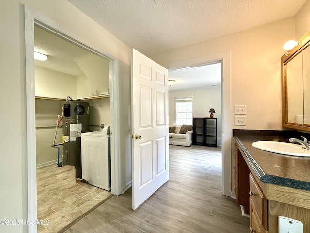 226 Community Rd, Lillington, NC 27546 - bathroom with washer / dryer, vanity, electric water heater, wood finished floors, and a textured ceiling