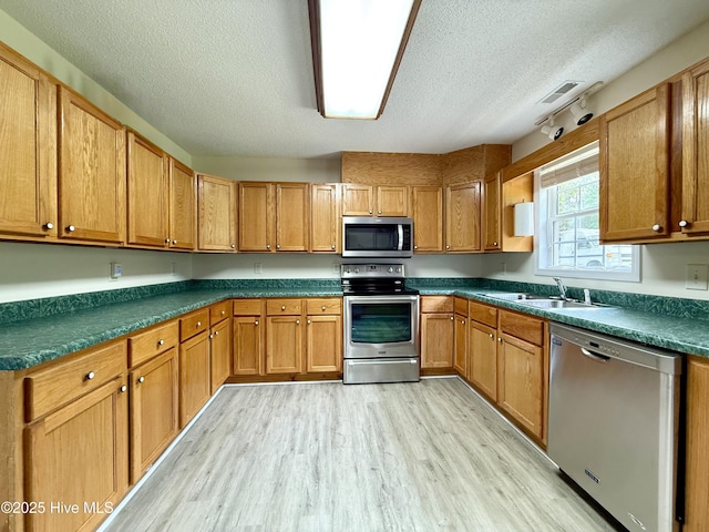 226 Community Rd, Lillington, NC 27546 - kitchen with stainless steel appliances, a textured ceiling, light wood-type flooring, dark countertops, and brown cabinets