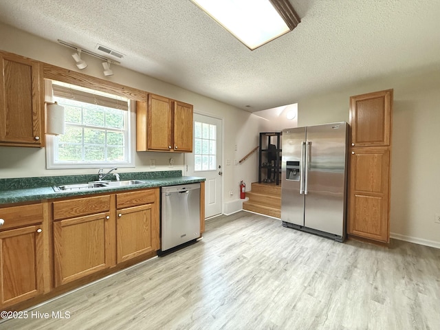 226 Community Rd, Lillington, NC 27546 - kitchen with stainless steel appliances, a textured ceiling, light wood finished floors, brown cabinetry, and dark countertops