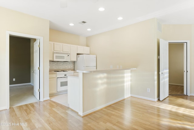 215 Royal Poste Rd Unit 2709, Sunset Beach, NC 28468 - kitchen featuring white appliances, light wood-type flooring, decorative backsplash, light countertops, and a peninsula