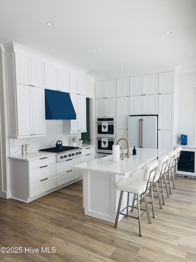1320 Searay Ln, Carolina Beach, NC 28428 - kitchen with white appliances, ventilation hood, a kitchen breakfast bar, white cabinetry, and light wood-style floors