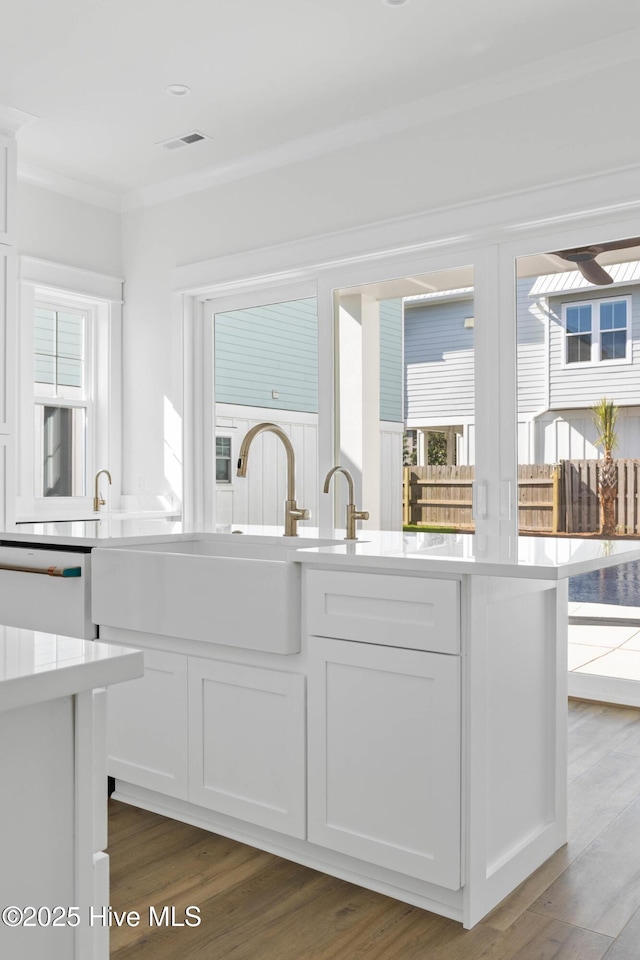 1320 Searay Ln, Carolina Beach, NC 28428 - kitchen featuring ornamental molding, white dishwasher, white cabinetry, light countertops, and wood finished floors
