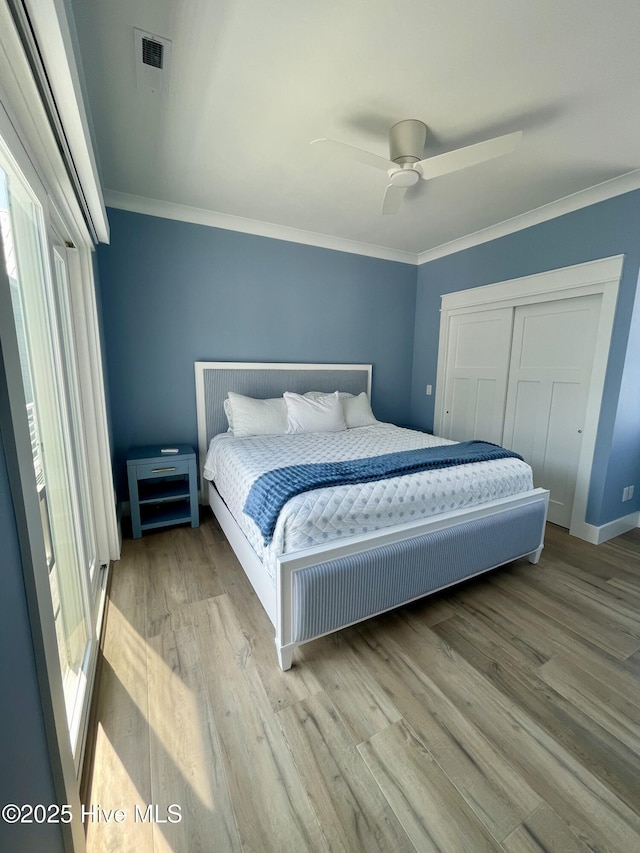 1320 Searay Ln, Carolina Beach, NC 28428 - bedroom with crown molding, multiple windows, wood finished floors, a closet, and a ceiling fan
