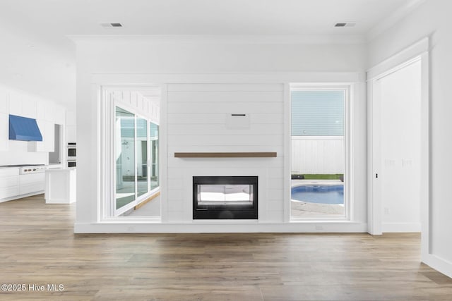 1320 Searay Ln, Carolina Beach, NC 28428 - unfurnished living room featuring ornamental molding, light wood-style flooring, and a large fireplace