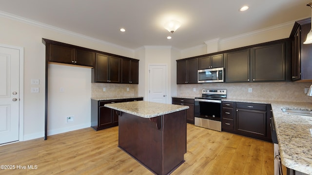 341 Oleander Dr, Greenville, NC 27858 - kitchen with stainless steel appliances, a kitchen island, light wood-style floors, dark brown cabinets, and ornamental molding
