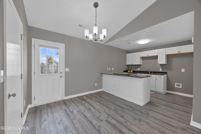 6739 Newbury Way, Wilmington, NC 28411 - kitchen featuring vaulted ceiling, dark countertops, a peninsula, white cabinets, and a chandelier