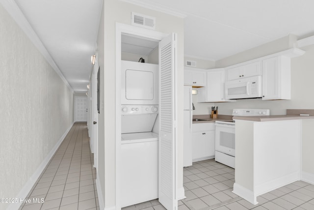 222 Carolina Beach Ave N Unit 230, Carolina Beach, NC 28428 - kitchen featuring white appliances, stacked washer and clothes dryer, white cabinetry, light tile patterned floors, and ornamental molding