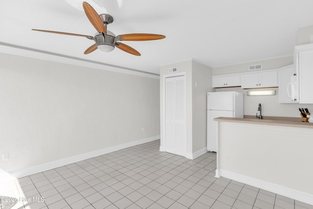 222 Carolina Beach Ave N Unit 230, Carolina Beach, NC 28428 - kitchen with freestanding refrigerator, a ceiling fan, white cabinets, light countertops, and ornamental molding
