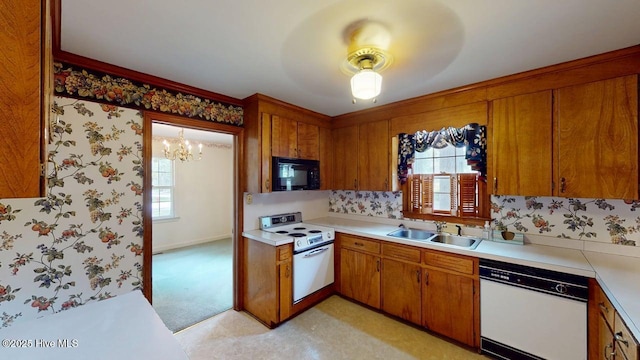 707 S Claiborne St, Goldsboro, NC 27530 - kitchen featuring white appliances, light countertops, brown cabinetry, a chandelier, and wallpapered walls