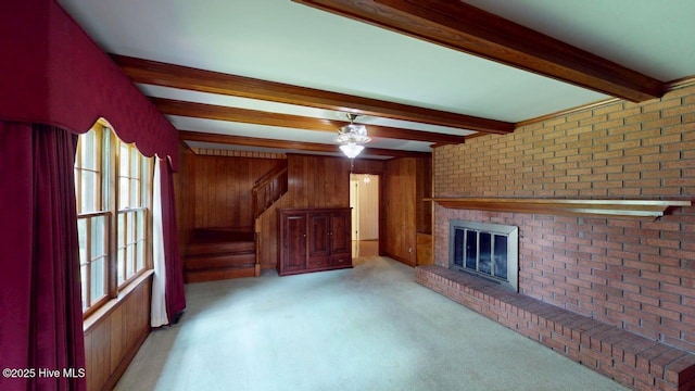 707 S Claiborne St, Goldsboro, NC 27530 - unfurnished living room with beamed ceiling, wood walls, a brick fireplace, ceiling fan, and light carpet