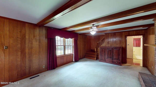 707 S Claiborne St, Goldsboro, NC 27530 - unfurnished living room featuring beam ceiling, wooden walls, stairway, a ceiling fan, and light carpet