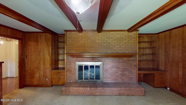 707 S Claiborne St, Goldsboro, NC 27530 - unfurnished living room featuring wood walls, beamed ceiling, carpet flooring, a fireplace, and built in shelves