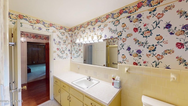 707 S Claiborne St, Goldsboro, NC 27530 - bathroom with wallpapered walls, wainscoting, vanity, and tile walls