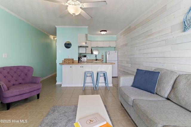 2224 New River Inlet Rd Unit 233, North Topsail Beach, NC 28460 - living room featuring ornamental molding, wooden walls, light tile patterned floors, and a ceiling fan