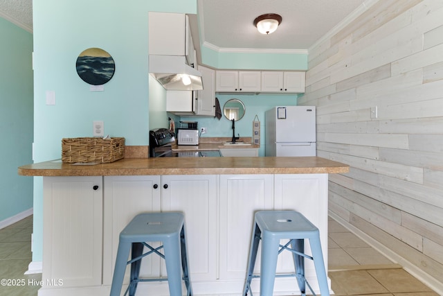 2224 New River Inlet Rd Unit 233, North Topsail Beach, NC 28460 - kitchen featuring freestanding refrigerator, range hood, crown molding, wood walls, and range