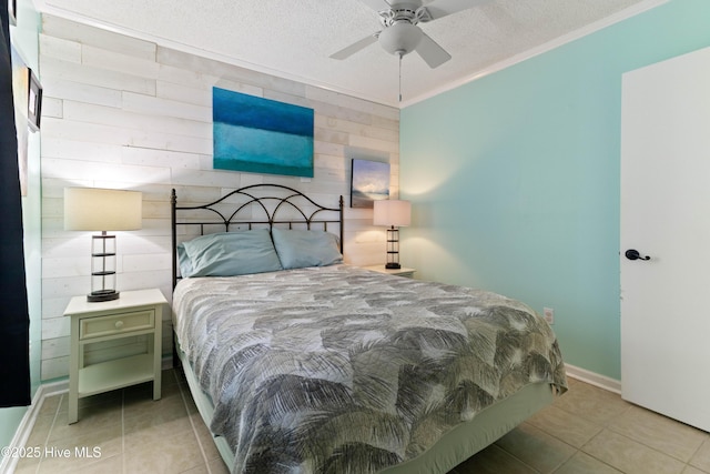 2224 New River Inlet Rd Unit 233, North Topsail Beach, NC 28460 - bedroom with tile patterned floors, a textured ceiling, wood walls, ceiling fan, and ornamental molding