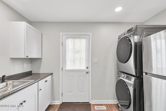 721 New River Dr, Jacksonville, NC 28540 - washroom with stacked washing machine and dryer, wood finished floors, cabinet space, and recessed lighting