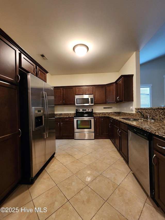 205 Channel Marker Loop, Swansboro, NC 28584 - kitchen with stainless steel appliances, dark brown cabinetry, light tile patterned floors, and dark stone counters