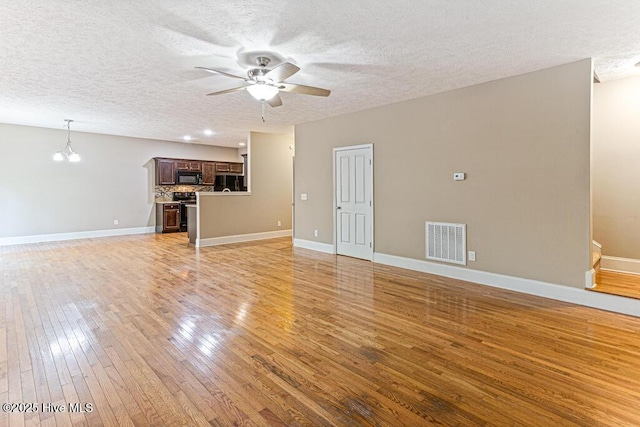 3 S Ct, Pinehurst, NC 28374 - unfurnished living room featuring a ceiling fan, light wood finished floors, a textured ceiling, and a chandelier