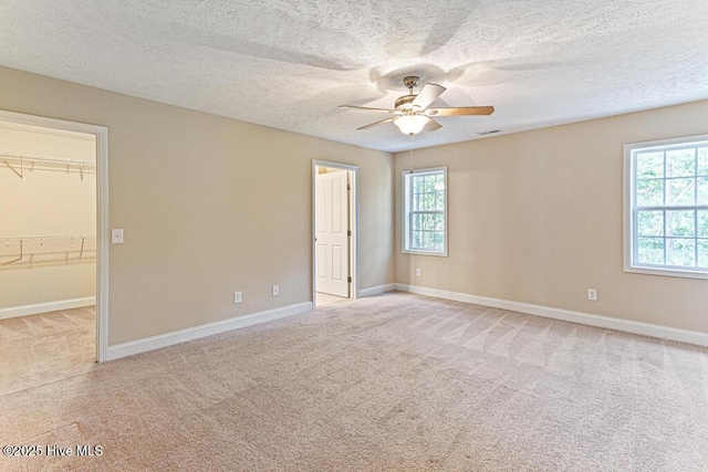 3 S Ct, Pinehurst, NC 28374 - unfurnished bedroom with light carpet, multiple windows, a walk in closet, ceiling fan, and a textured ceiling