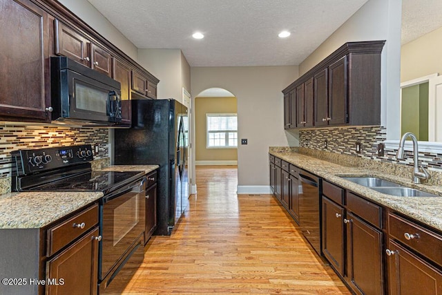 3 S Ct, Pinehurst, NC 28374 - kitchen featuring black appliances, arched walkways, light wood-style flooring, a textured ceiling, and dark brown cabinetry