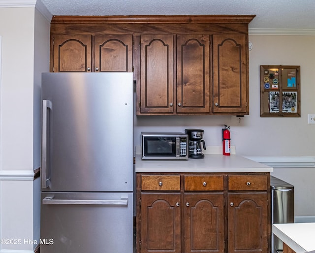 306 Goldleaf Dr, Goldsboro, NC 27534 - kitchen featuring appliances with stainless steel finishes, light countertops, crown molding, dark brown cabinets, and a textured ceiling