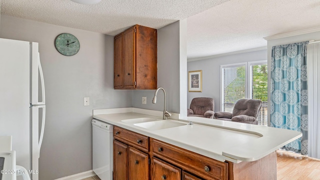 800 Saint Andrews Dr # 156, Pinehurst, NC 28374 - kitchen with white appliances, light countertops, a textured ceiling, brown cabinetry, and crown molding