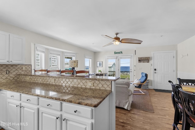 1711 Carolina Beach Ave N Unit B, Carolina Beach, NC 28428 - kitchen featuring a peninsula, wood finished floors, white cabinetry, a ceiling fan, and decorative backsplash