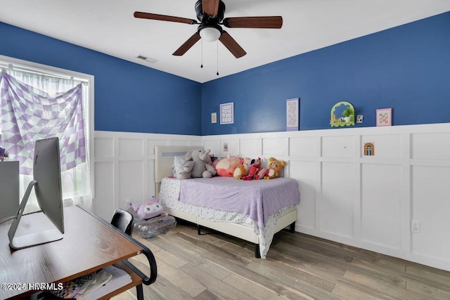 939 Dynamo Ln, Jacksonville, NC 28546 - bedroom featuring a decorative wall, a wainscoted wall, wood finished floors, and ceiling fan
