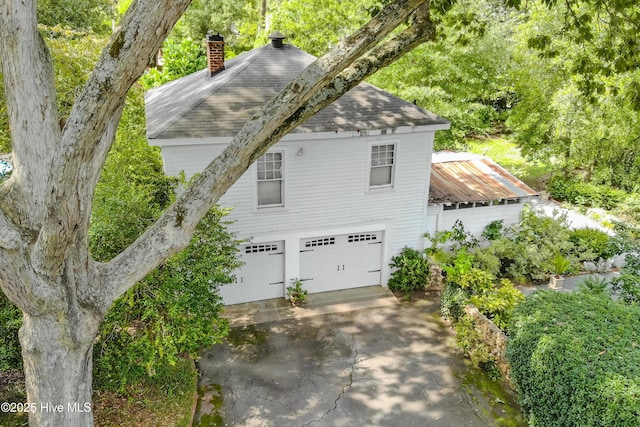 900 Nash St N, Wilson, NC 27893 - view of side of property with a garage, a chimney, a shingled roof, and driveway