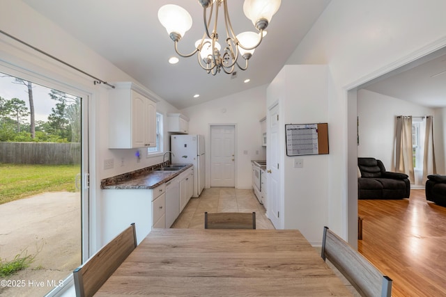 32 S Shelby Rd, Southport, NC 28461 - kitchen with lofted ceiling, dark countertops, plenty of natural light, a chandelier, and white appliances