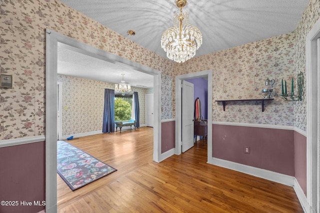 1710 National Ave, New Bern, NC 28560 - unfurnished dining area with a chandelier, wood finished floors, wallpapered walls, and a textured ceiling