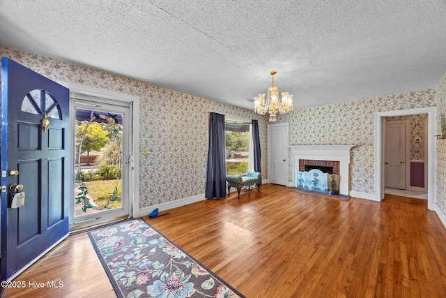 1710 National Ave, New Bern, NC 28560 - unfurnished living room featuring wallpapered walls, a chandelier, wood finished floors, a textured ceiling, and a fireplace