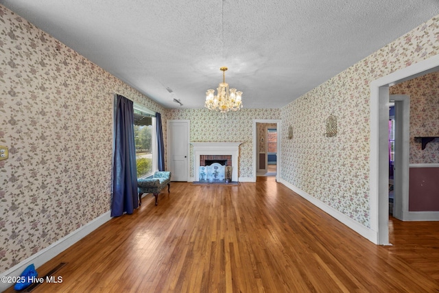 1710 National Ave, New Bern, NC 28560 - unfurnished living room with wallpapered walls, wood finished floors, a textured ceiling, a chandelier, and a fireplace