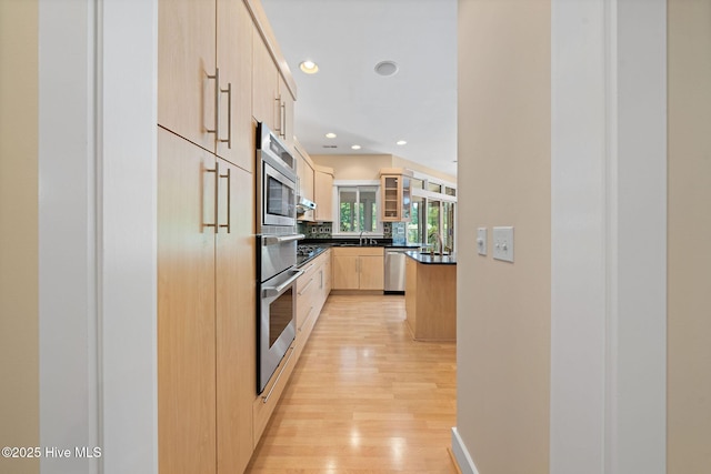 2945 Moorings Way SE, Southport, NC 28461 - kitchen featuring appliances with stainless steel finishes, light brown cabinetry, dark countertops, recessed lighting, and light wood finished floors