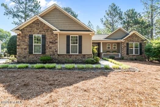 124 Juniper Creek Blvd Unit 16, Pinehurst, NC 28374 - view of front of house featuring stone siding and covered porch