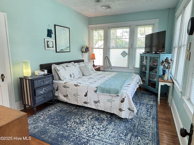 124 W Main St, Woodland, NC 27897 - bedroom with wood finished floors, multiple windows, and a textured ceiling