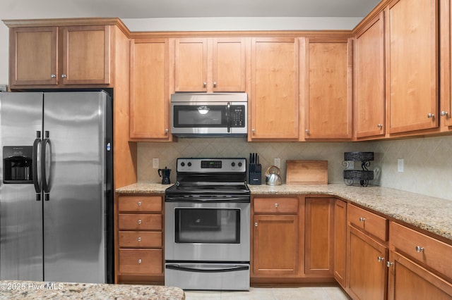 213 Wynbrookee Ln, Jacksonville, NC 28546 - kitchen featuring stainless steel appliances, light stone countertops, tasteful backsplash, light tile patterned floors, and brown cabinets