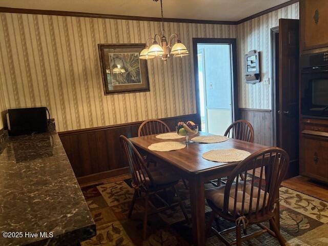 2904 Jason Dr, Rocky Mount, NC 27803 - dining area featuring crown molding, a wainscoted wall, a chandelier, wood finished floors, and wooden walls