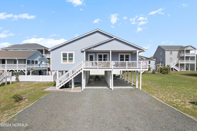 130 Crab St, Holden Beach, NC 28462 - view of front of property with stairway, gravel driveway, a carport, a front lawn, and a porch
