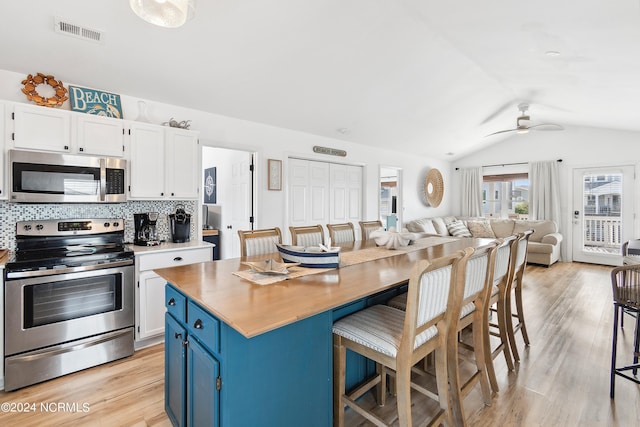 130 Crab St, Holden Beach, NC 28462 - kitchen featuring stainless steel appliances, blue cabinetry, open floor plan, vaulted ceiling, and light wood-type flooring