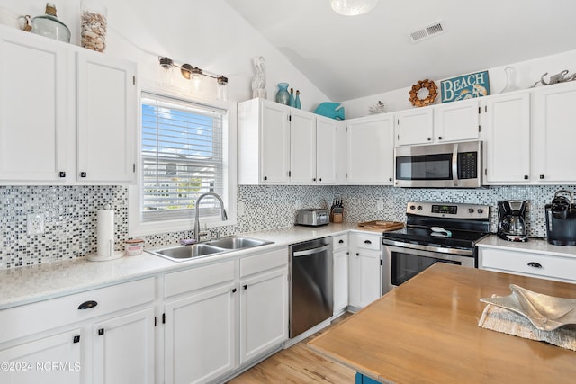 130 Crab St, Holden Beach, NC 28462 - kitchen with appliances with stainless steel finishes, tasteful backsplash, white cabinetry, and vaulted ceiling