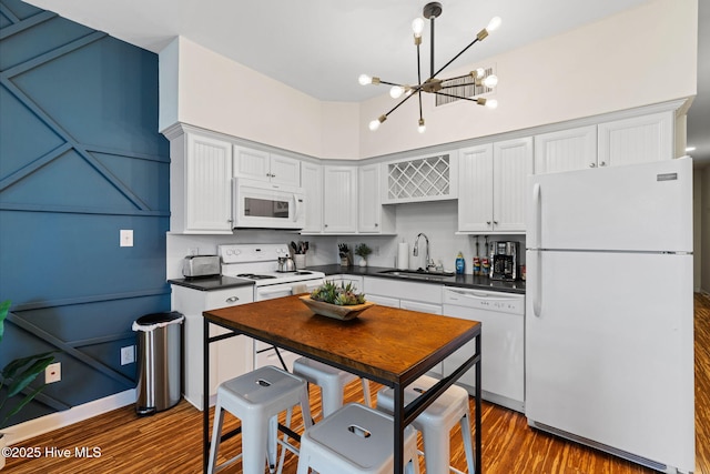 215 S Water St Apt 206, Wilmington, NC 28401 - kitchen featuring white appliances, dark countertops, dark wood finished floors, a chandelier, and white cabinets