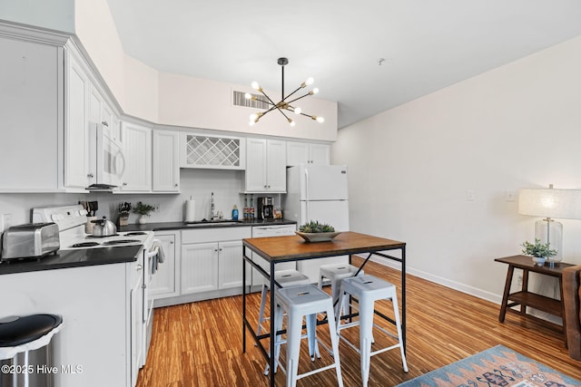 215 S Water St Apt 206, Wilmington, NC 28401 - kitchen featuring white appliances, dark countertops, a chandelier, light wood-style floors, and pendant lighting