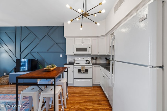 215 S Water St Apt 206, Wilmington, NC 28401 - kitchen featuring white appliances, dark countertops, a chandelier, wood finished floors, and white cabinets