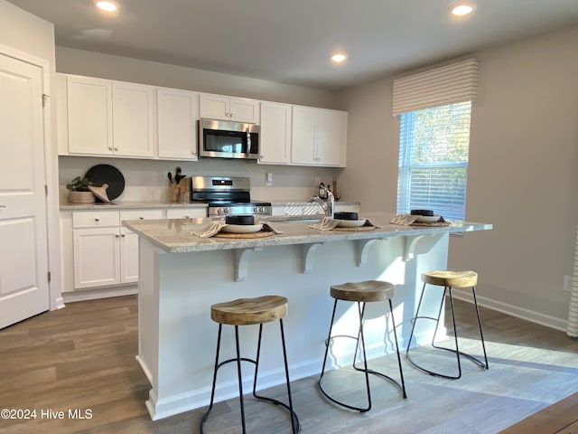 5191 Meagan Ln NE, Winnabow, NC 28479 - kitchen with appliances with stainless steel finishes, wood finished floors, white cabinetry, a breakfast bar, and recessed lighting